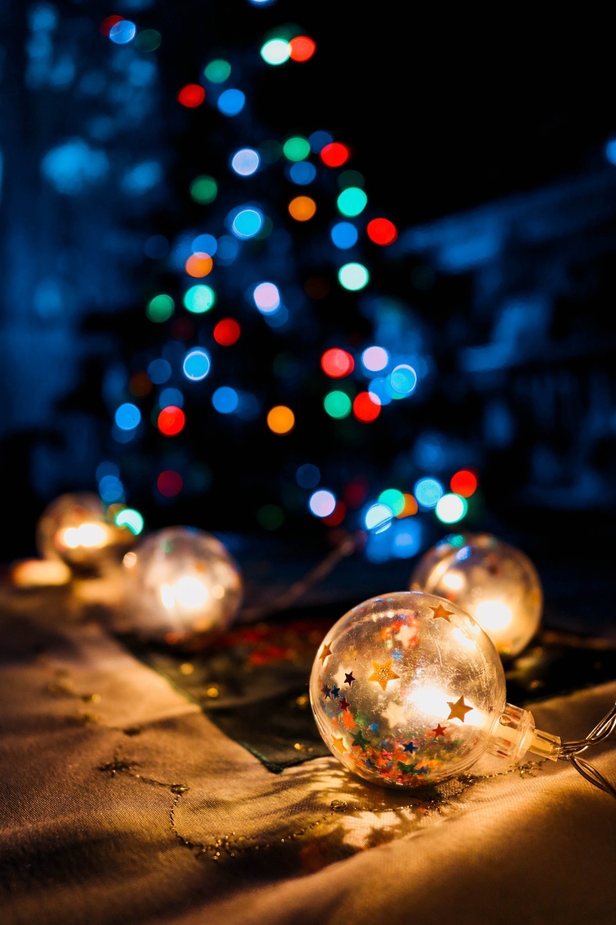 Een duidelijke kerstbal en wazige kerstballen met een kerstboom in de achtergrond